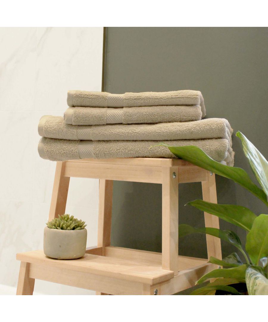 Beige cotton towels stacked neatly on a wooden ladder, accompanied by a small potted plant, against a dark green wall.