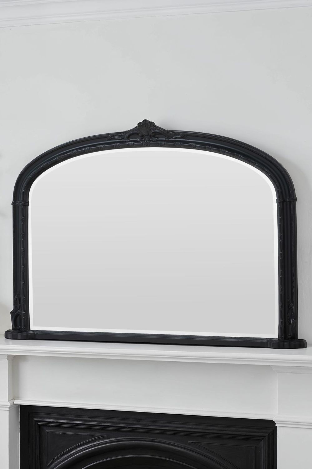 Victorian-style arched overmantle mirror in black, measuring 127cm wide by 89cm high, featuring intricate detailing along the top edge.