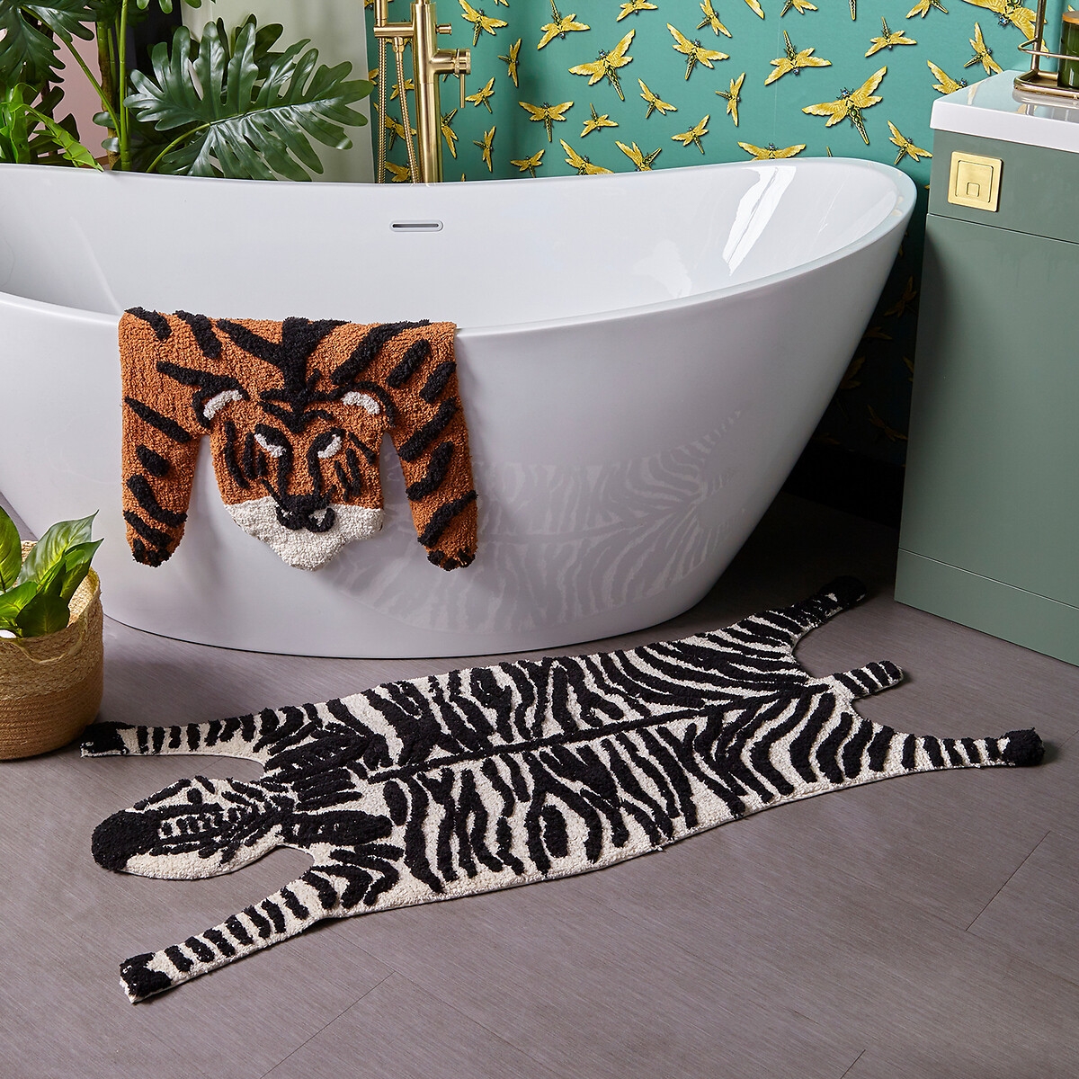 Zebra-shaped cotton bath mat in black and white with an anti-slip backing, placed beside a modern white bathtub, complemented by a matching zebra towel hanging nearby.
