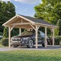 Wooden carport with pitched roof, natural finish, housing a car, surrounded by greenery and trees.