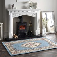 Blue circular rug with intricate floral patterns and beige border, placed in a cozy living room setting.
