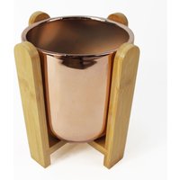 Gold ceramic planter, 16cm, with a smooth finish, set in a natural bamboo stand with curved supports.