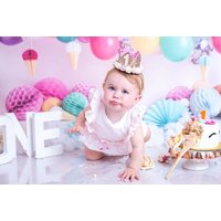 Baby in pink outfit and crown, surrounded by colorful balloons and cake, for 1st birthday photoshoot prints in Glasgow.