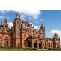 Historic red sandstone building with ornate towers and arches under a blue sky.