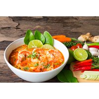 White bowl of Italian pasta with tomato sauce, garnished with lime slices and basil, surrounded by fresh vegetables.