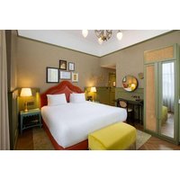 Deluxe King Room with red headboard, white bedding, yellow ottoman, vintage decor, and warm lighting at Elmbank Hotel.