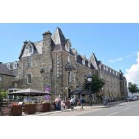 Fisher's Hotel in Pitlochry, a stone building with peaked roofs, outdoor seating, and street view.