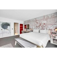 Modern hotel room with white bed, artistic wall mural, red accents, and sleek furnishings at Radisson Red Glasgow.