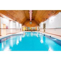 Indoor pool with wooden ceiling, blue water, and leisure seating area at Stirling Highland Hotel for afternoon tea experience.