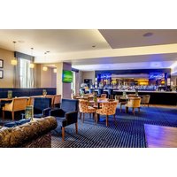 Elegant dining area with modern decor, plush chairs, and a well-stocked bar at Hotel Colessio, Stirling.