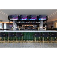 Chop Grill and Bar interior with green bar, black stools, and multiple TVs displaying sports.