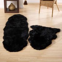Black sheepskin rug with a soft, fluffy texture, oval shape, placed on a light wooden floor.