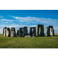 Ancient stone circle with large upright stones under a blue sky with clouds.