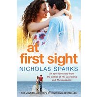 "At First Sight" book by Nicholas Sparks, cover showing a couple embracing with a blue sky background.