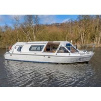 White Bella Donna boat by Hoseasons with blue trim, large windows, and open deck, cruising on a calm river.