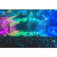 Concert stage with vibrant multicolored lights, confetti, and a crowd of people with raised hands and phones.