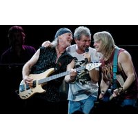 Band performing on stage, guitarist in black sleeveless shirt, singer in white tee, another guitarist in red tank top.