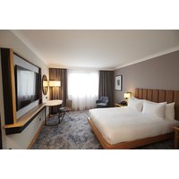 Queen room with large bed, wall-mounted TV, round table, armchair, and window with curtains at DoubleTree by Hilton Swindon.