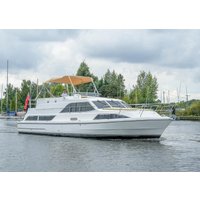 White "Evita" motor cruiser by Hoseasons with a beige canopy, large windows, and sleek design on a calm waterway.