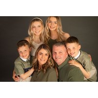 Family photoshoot package with smiling parents and four children, neutral backdrop, includes five printed photos.