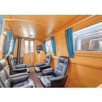 Interior of "Gloria" narrowboat by Hoseasons, featuring black leather recliners, wood paneling, and blue curtains.