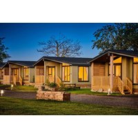 Luxury lodges with wooden porches, large windows, and ambient lighting at Silverwood Resort during twilight.