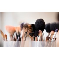 Assorted makeup brushes with black and brown bristles in a clear holder.
