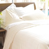 White organic cotton king fitted sheet on a bed, smooth texture, paired with matching pillowcases and duvet.