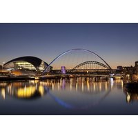 Newcastle cityscape at dusk with illuminated bridges and waterfront reflecting in the river.