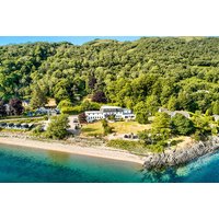 Scottish Highlands beach pod, nestled in lush greenery by a serene shoreline, accommodates four with breakfast included.