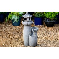 Stone Serenity Cascading Pagoda Water Feature with two-tiered bowls and a pagoda top, set on gravel with plants behind.