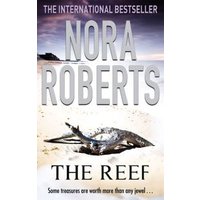"The Reef" book by Nora Roberts, cover features a beach scene with a washed-up shipwreck and dramatic sky.