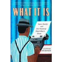 Book cover of "What It Is" featuring a man in a striped shirt typing on a typewriter against a blue curtain backdrop.