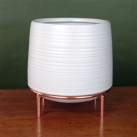 White ceramic planter with ribbed texture on a copper metal stand, suitable for indoor plants.