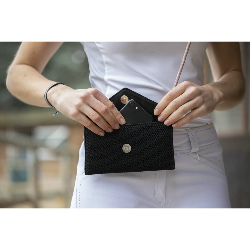 Black mesh phone pouch with a snap closure, featuring a triangular flap and a strap, held by a person wearing a white top and pants, with a smartphone partially visible inside.