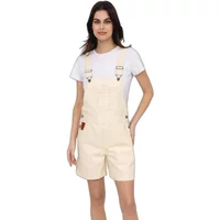 Cream women’s dungaree shorts with adjustable straps, front pocket, and side buttons, worn over a white t-shirt.