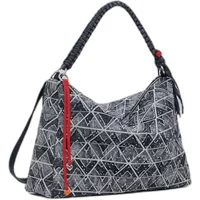 Black and white geometric-patterned Desigual shoulder bag with braided handle and red tassel accent.