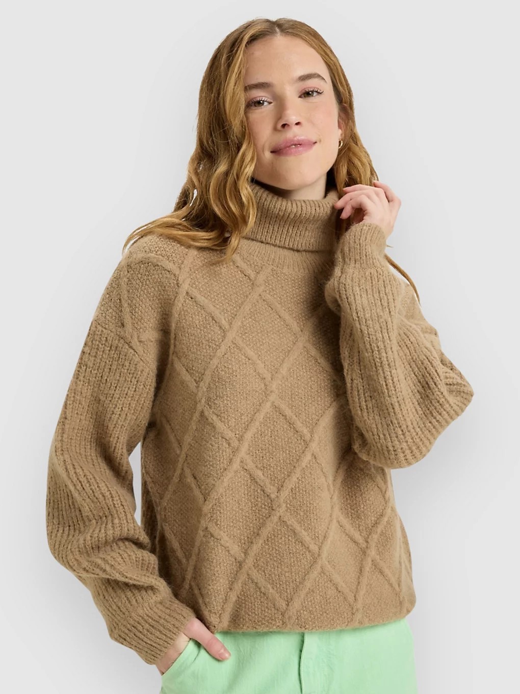 Brown knitted sweater with a high neck, featuring a diamond pattern and loose sleeves, styled with a relaxed fit.