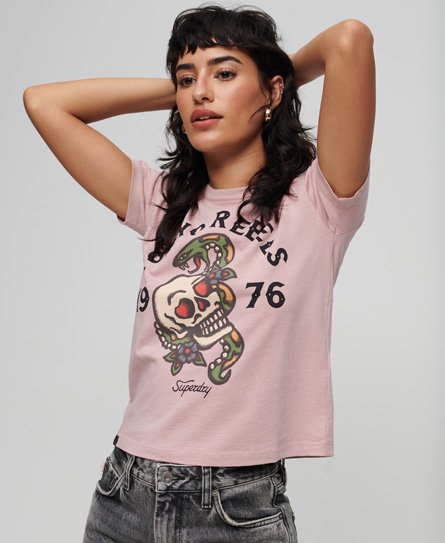 Pink 90s fit T-shirt featuring a colorful skull and floral tattoo graphic, with "Superdry" and "1976" text, made from soft cotton material, styled with rolled sleeves.