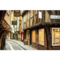 Narrow cobblestone street with historic timber-framed buildings and illuminated shop signs.