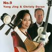 Yang Jing holds a traditional pipa, while Christy Doran stands beside her with a white electric guitar, both against a plain white background.