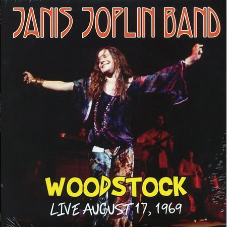 A vibrant album cover featuring Janis Joplin performing live, wearing a colorful, flowing outfit with a tie-dye pattern, set against a dark stage backdrop with bold text.