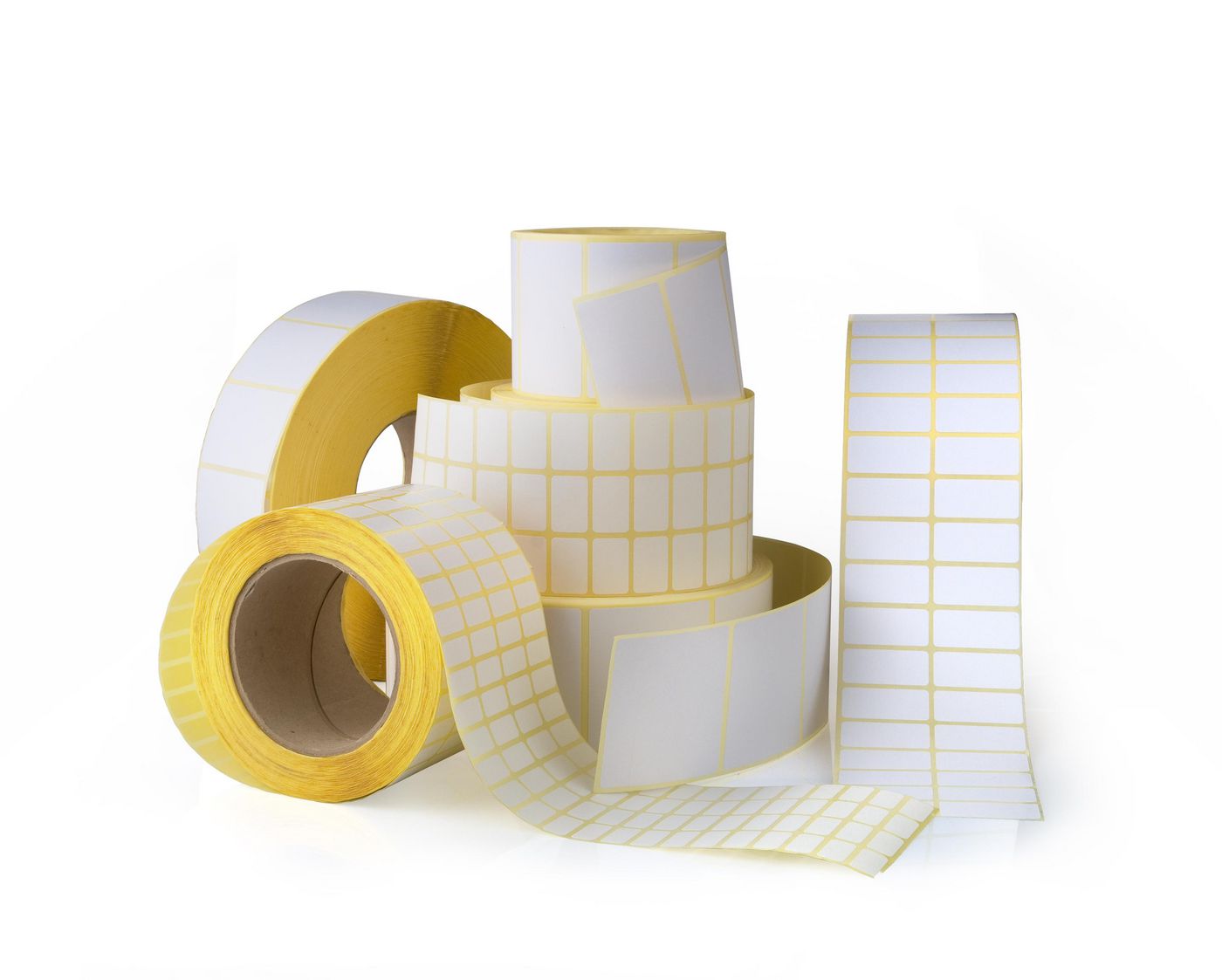 White printer labels with yellow backing, rolled in various sizes and stacked, featuring a grid pattern for easy labeling and organization.