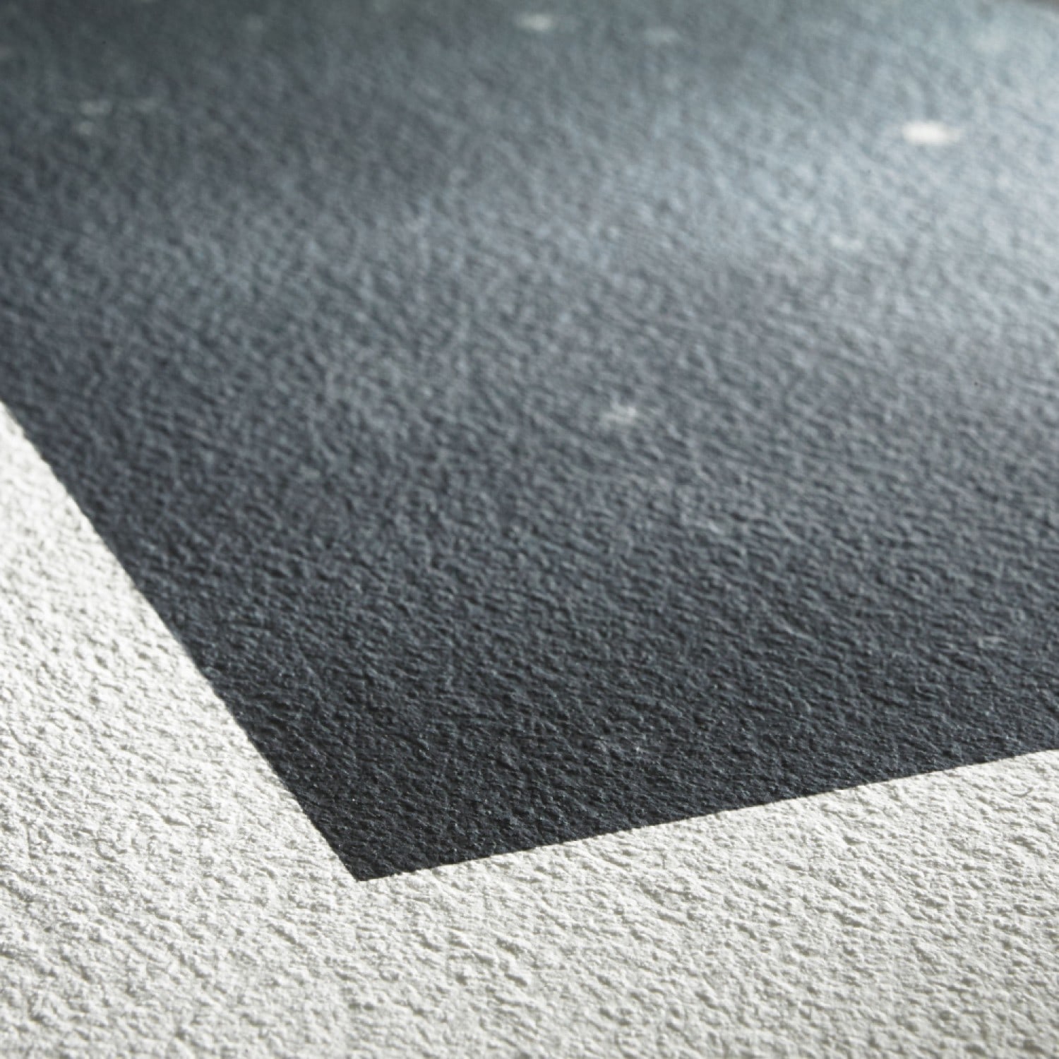 Textured paper with a smooth, white edge and a gradient of dark to light grey tones, showcasing a fine art quality suitable for prints and drawings.