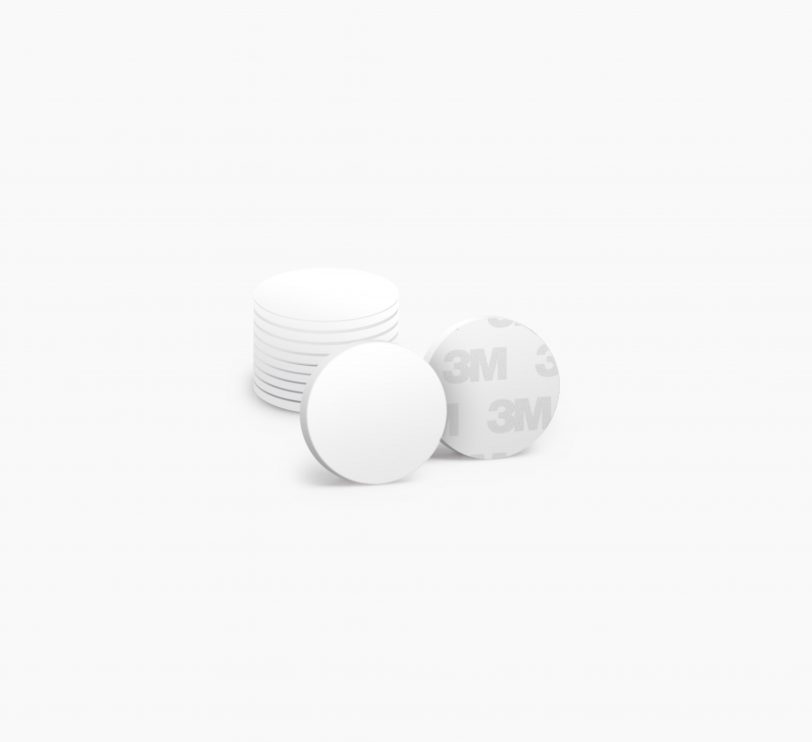 White self-adhesive proximity discs with a smooth surface, featuring a 3M backing, arranged in a stack of ten.