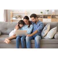 Family using laptop on gray sofa, promoting Online Mental Maths Family Pack Subscription for multi-device learning.