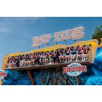 Colorful ride at M&D's Scotland's Theme Park with "Rip Tide" sign, featuring seated riders against a blue sky backdrop.