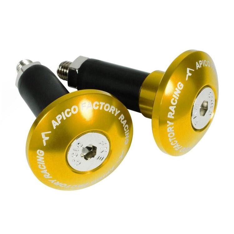 Gold anodized aluminum handlebar bar end plugs with a black rubber core, featuring "APICO FACTORY RACING" engraved around the edge and a central hex screw for installation.