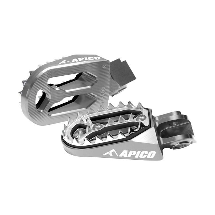 Apico Pro-Bite foot pegs in titanium finish, featuring a rugged design with serrated edges for grip, compatible with KTM SX65, SX250, and EXC-F models from various years.