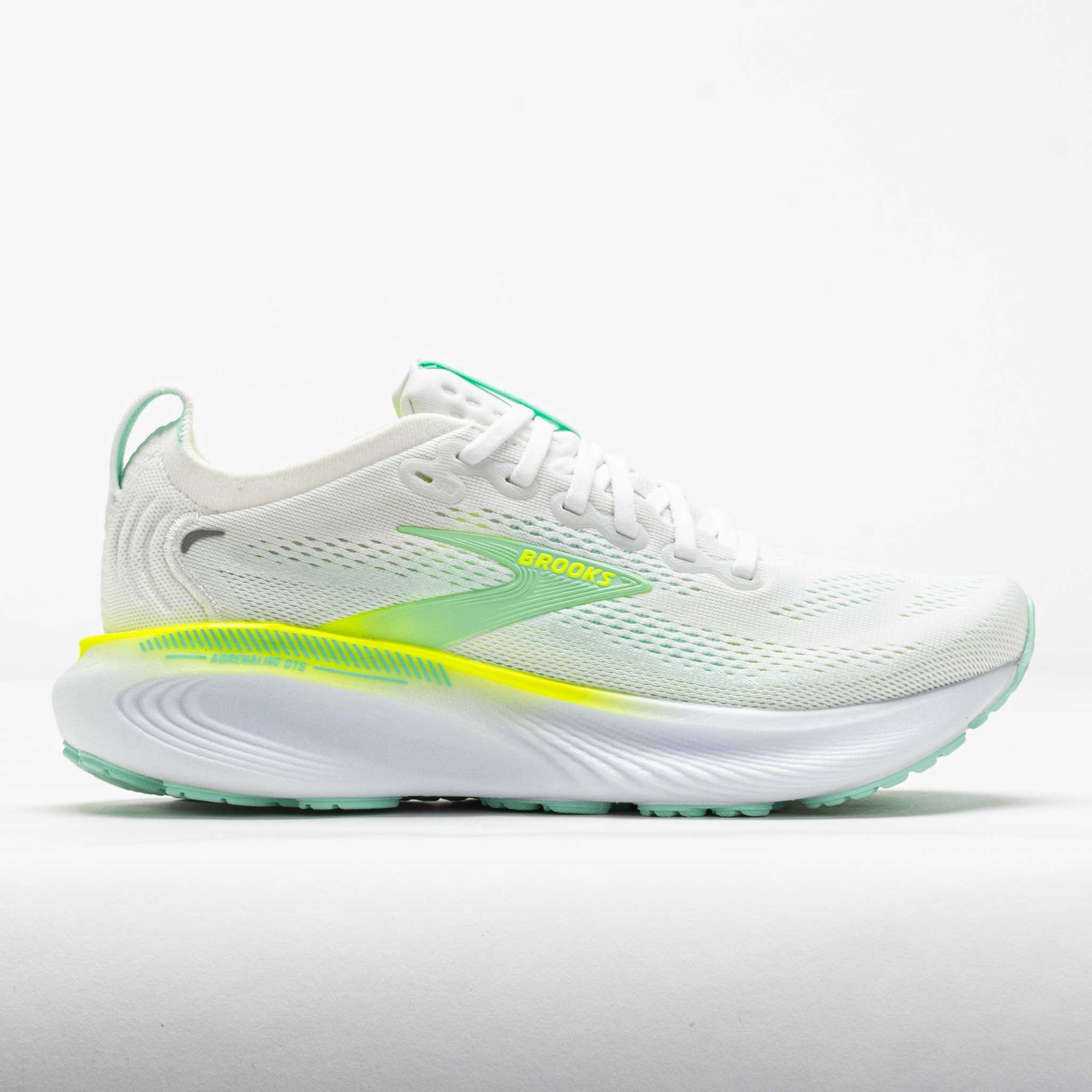 Women's Brooks Adrenaline GTS 25 running shoes in white with green and yellow accents, featuring a breathable mesh upper and cushioned sole for comfort and support.